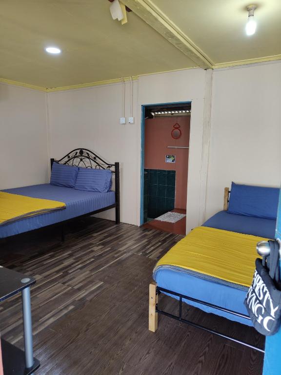 a room with two beds and a door to a bathroom at Permata Beach Chalet in Kampong Juara