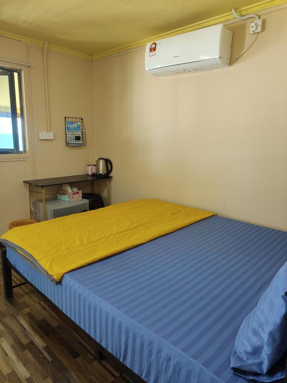a bedroom with a bed with a yellow blanket at Permata Beach Chalet in Kampong Juara