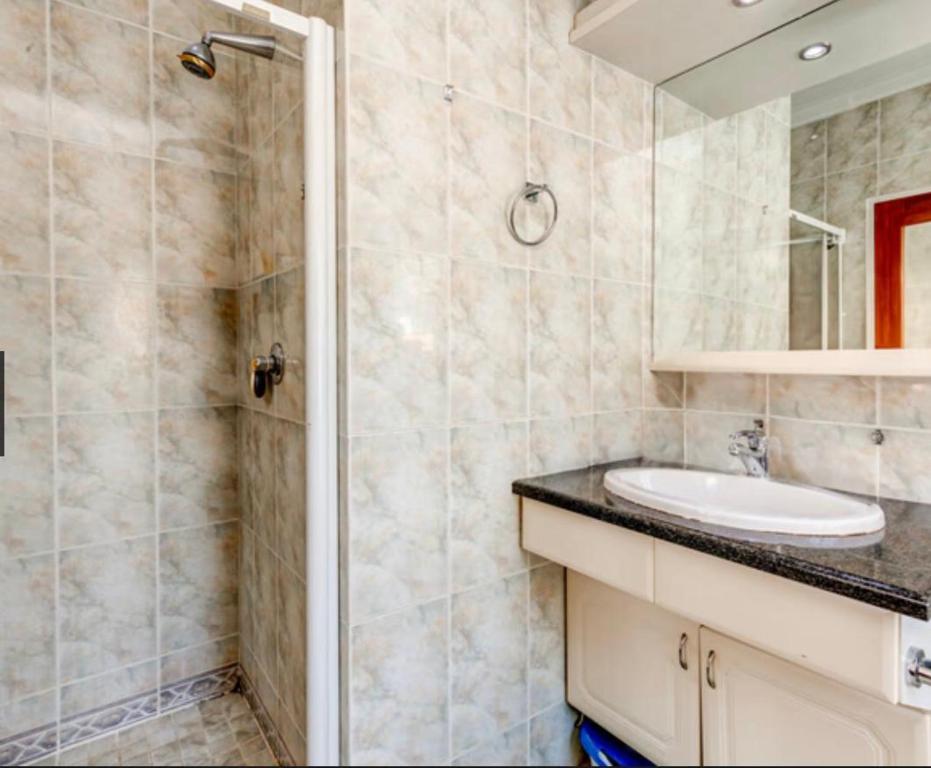 un baño con lavabo y ducha en Heartwood haven, en Sandton