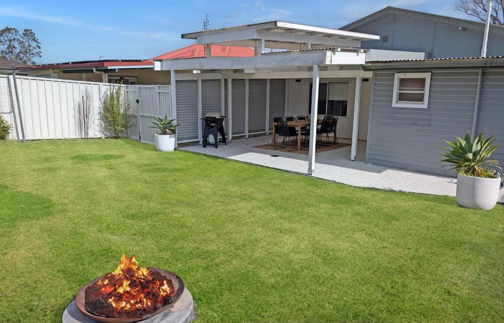 a backyard with a fire pit in the grass at Husky Beach House by Experience Jervis Bay in Huskisson