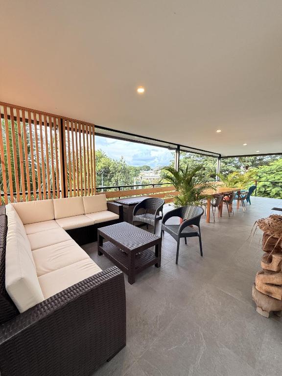 a living room with a couch and chairs and tables at Ononui Lodge Airport, Ocean-View, Private Bathroom and Balcony, Free WiFi and Parking, On-Site Car Rental in Faaa
