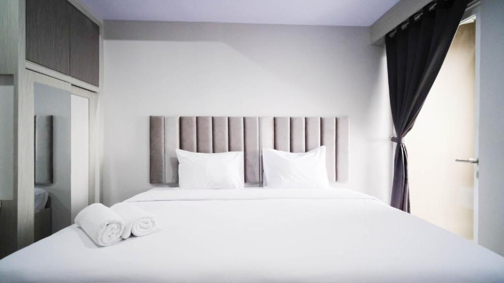 Un dormitorio con una gran cama blanca con almohadas blancas. en Nice and Comfy Studio at Grand Dharmahusada Lagoon Apartment By Travelio, en Surabaya
