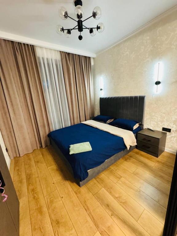 una camera da letto con un letto blu e un lampadario di Бишкек Парк a Bishkek