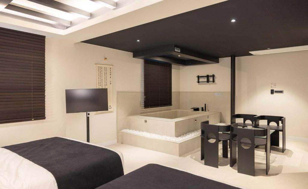 a bedroom with a tub and a bed and chairs at Anook Hotel and Spa Seoul Jongno Anguk 1st in Seoul