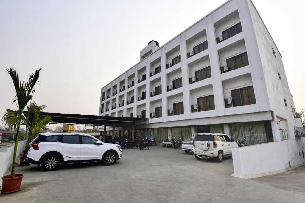 a large white building with cars parked in a parking lot at Hotel Devanshi & Banquets by Classy Stay in Navi Mumbai