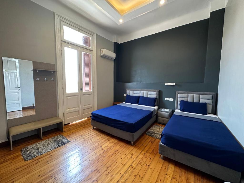 2 Betten in einem Zimmer mit blauer Bettwäsche in der Unterkunft Cairo Hub in Kairo