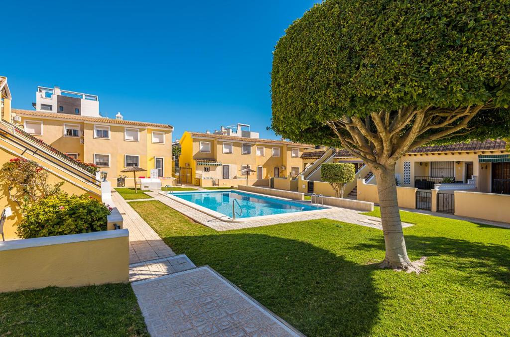 een zwembad in een tuin met een boom bij Casa Fre - Lomas Del Golf - Villamartin in Villamartin