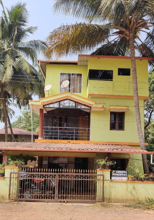 a yellow house with a palm tree in front of it at Christa Homestay in Mangalore