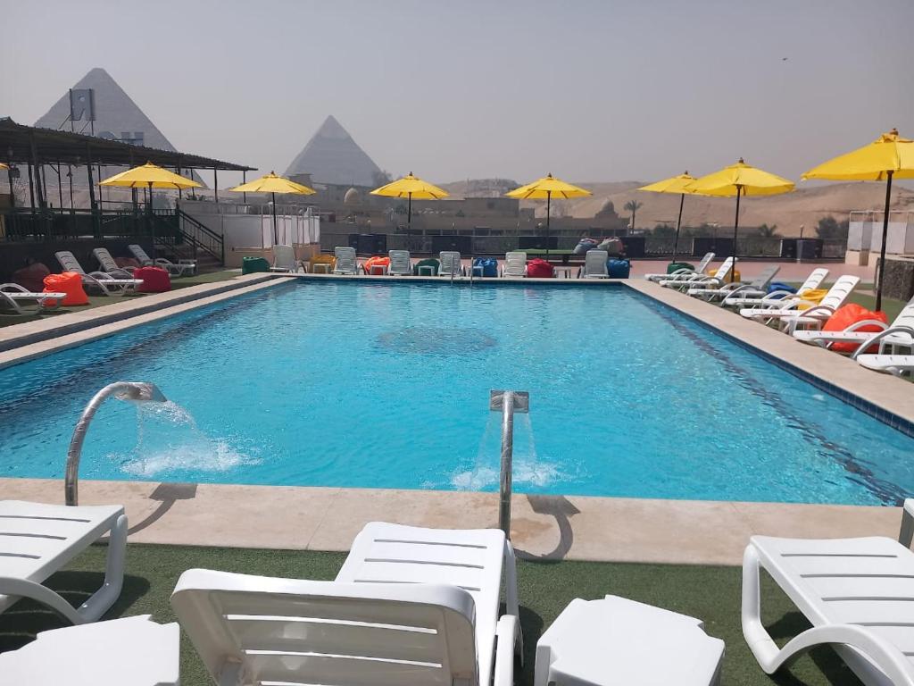 a large swimming pool with chairs and umbrellas at Pyramids regense in Cairo