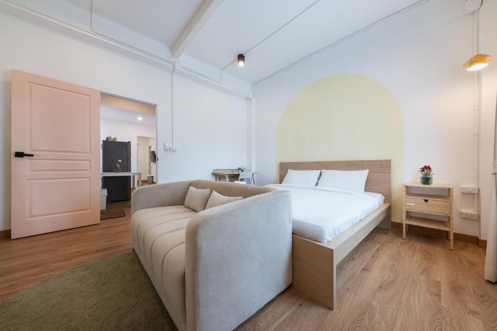 a white bedroom with a bed and a couch at Marshmallow House in Sathani Lak Si