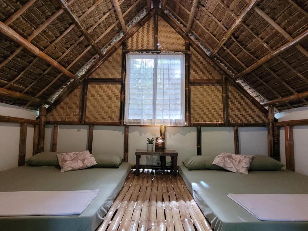 a room with two beds in a building with a window at Lazy Lizard Hostel in Siquijor