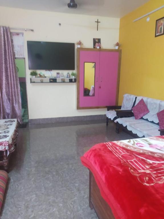 a room with a tv and a bed and a couch at Relish Homestay in Prayagraj