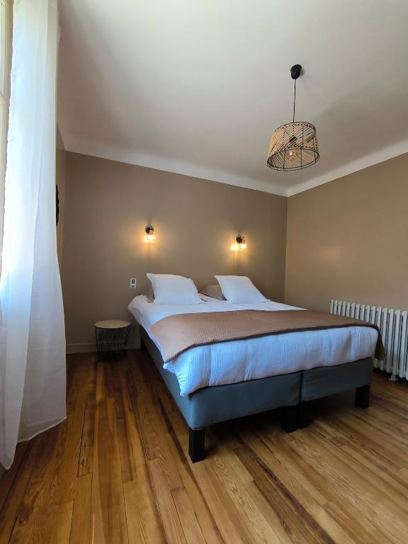 une chambre avec un grand lit et un lustre dans l'établissement Appartement 6 pers, 3 chambres, au 1er étage, d'une maison à Luz Saint Sauveur, Hautes-Pyrénées, à Luz-Saint-Sauveur