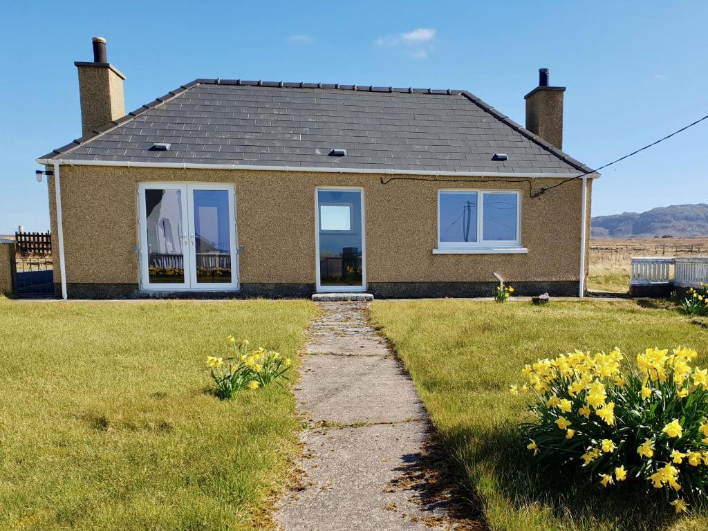 a small house with a grass yard with yellow flowers at Bayview in Bragor