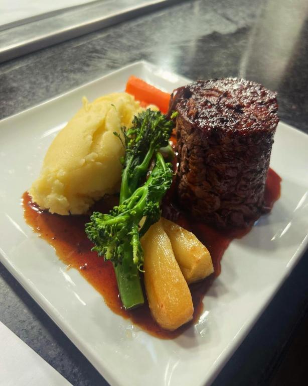a plate of food with steak and mashed potatoes and broccoli at Bowood Park Hotel in Camelford