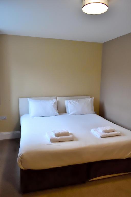 a large white bed with two towels on it at Bowood Park Hotel in Camelford