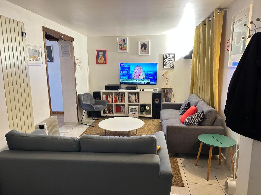 un salon avec des canapés et une télévision à écran plat dans l'établissement Aubervilliers maison de ville près métro 7 by immo kit bnb, à Aubervilliers