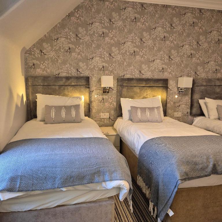 a bedroom with two beds and a stone wall at Kintrae B&B in Buckie