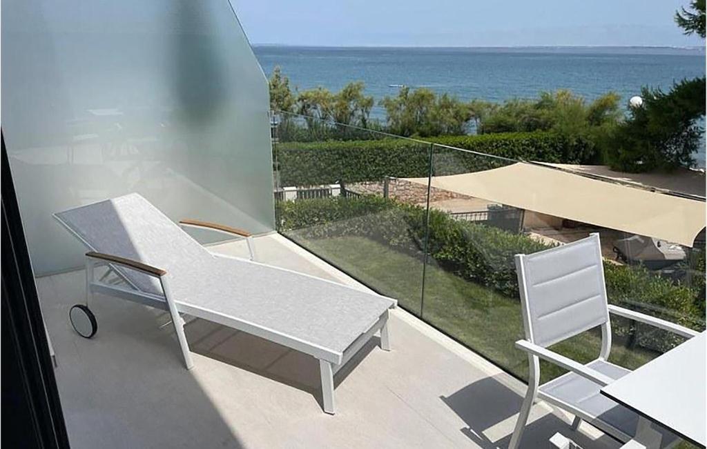 un banco blanco y 2 sillas en un balcón con vistas al océano en 1 Bedroom Awesome Apartment In Ugljan, en Ugljan