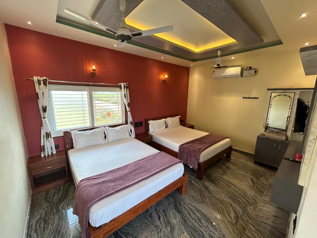 a small room with two beds and a mirror at Anu Paradise Hampi in Hampi