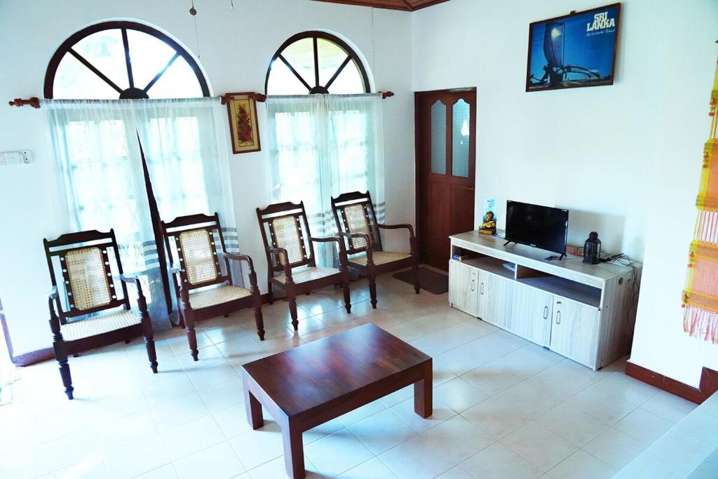a living room with chairs and a table and a tv at Eco Villa in Ambalangoda