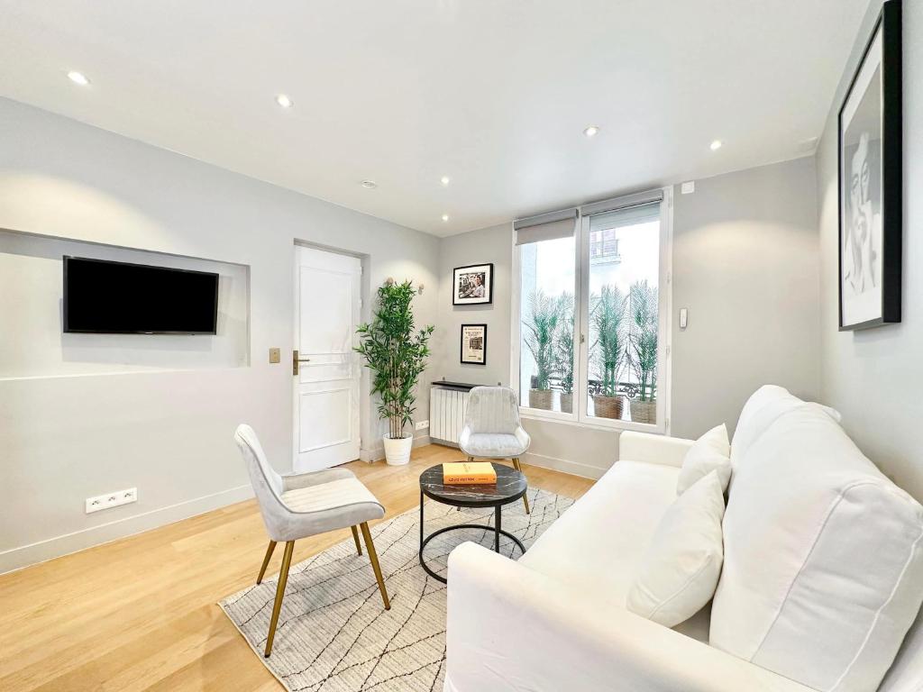 un salon avec un canapé blanc et une télévision dans l'établissement Deluxe apartment near the Tour Eiffel, à Paris