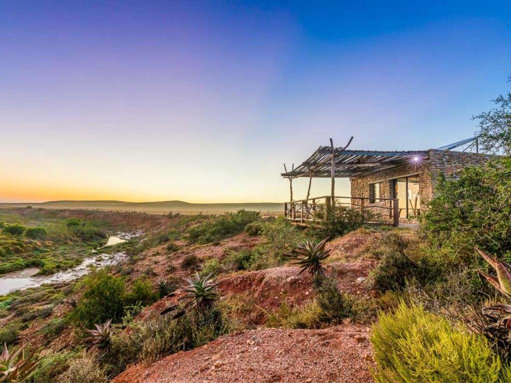 a house on a hill with the ocean in the background at Canyon Cottage in Cloeteskraal