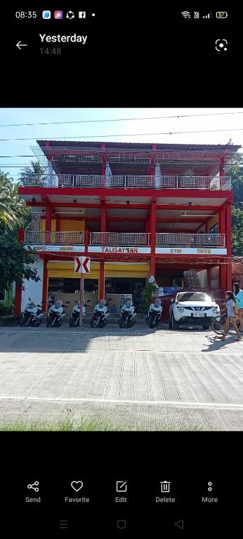 a red building with motorcycles parked in front of it at Talisay Inn in Anda