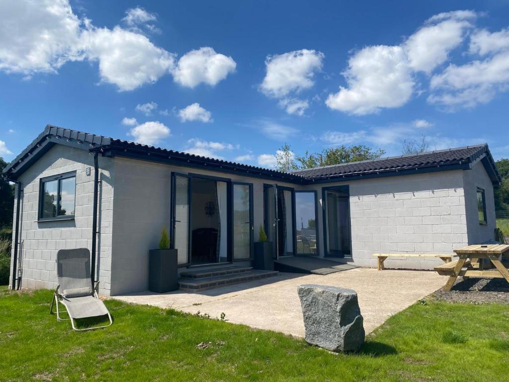 a small white house with a picnic table and a bench at HORSESHOE LUXURY ACCESSIBLE LODGE Sleeps 4 at Fairview Farm in Ravenshead Nottingham near Sherwood Forest ,Dog Friendly Farm Stay in Blidworth