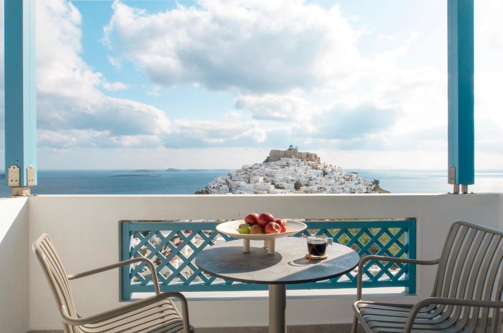 a table on a balcony with a view of the ocean at Andromeda Resort in Astypalaia