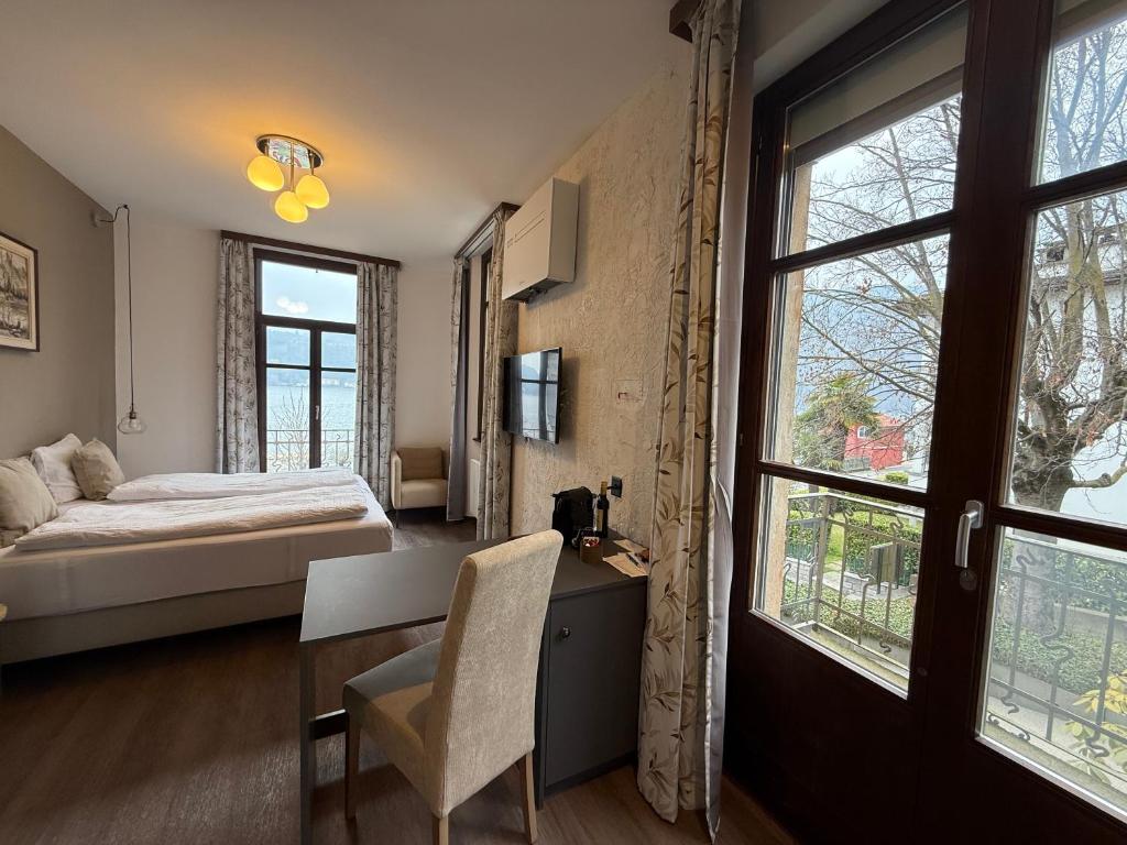 una camera con letto, scrivania e finestre di Arbostora Charme Hotel a Morcote