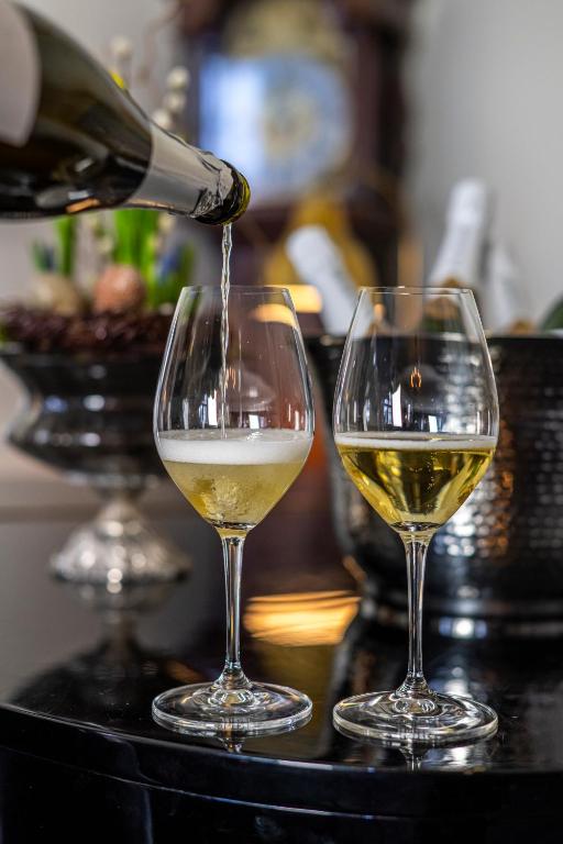 two wine glasses with white wine being poured into them at Gl. Avernæs Sinatur Hotel & Konference in Ebberup