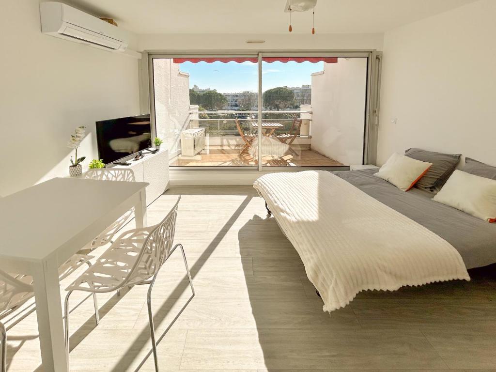 - une chambre avec un lit, une table et un balcon dans l'établissement Pacific - studio avec terrasse parking et clim, à La Grande Motte