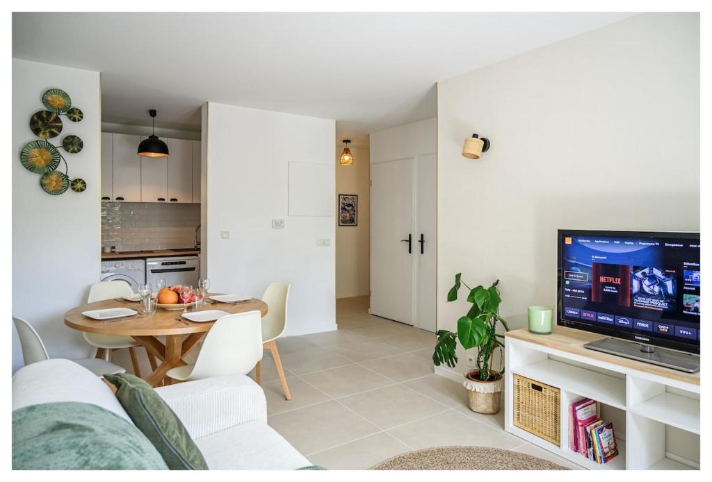 a living room and kitchen with a table and a television at Charmant 2 pièces proche Disney & Paris avec jardin et Parking in Collégien