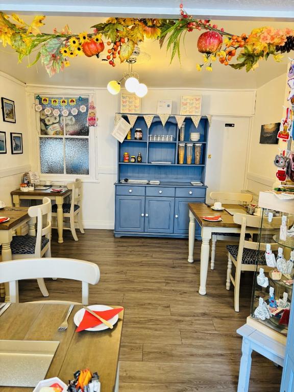 a restaurant with blue cabinets and wooden tables at Carnson House in Penzance