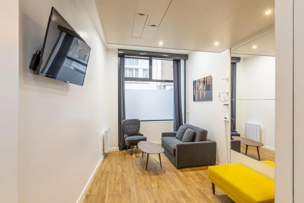 un salon avec un canapé et une télévision sur un mur dans l'établissement Cosy studio 2 - Grenelle Eiffel Tower, à Paris