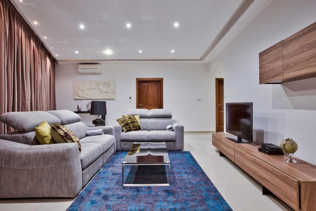 a living room with two couches and a tv at Modern 200sqm 4 bedroom Apartment with side sea view Sleeps 11 in Sliema