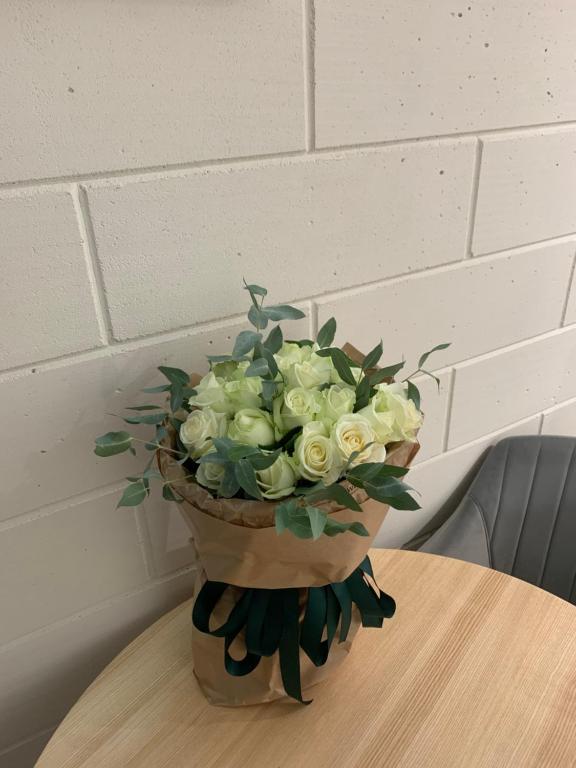 a bouquet of white roses in a vase on a table at Апартаменти Dream Space in Khmelʼnytsʼkyy