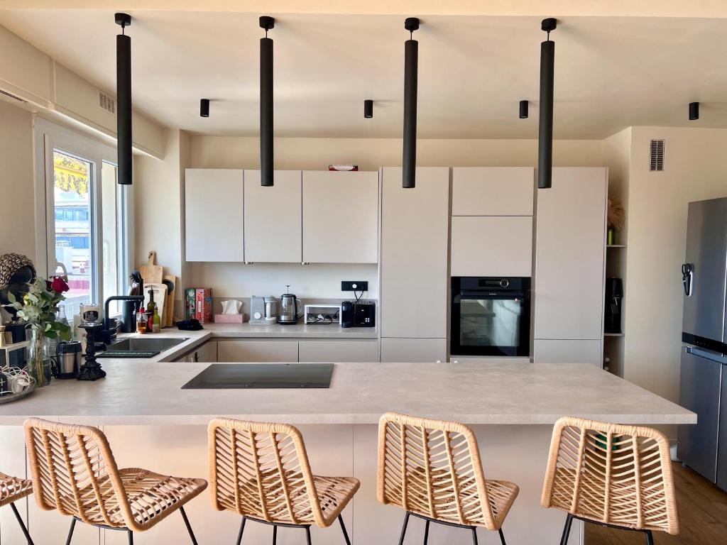 une cuisine avec un grand îlot blanc avec des chaises dans l'établissement Cannes quartier des anglais, à Cannes