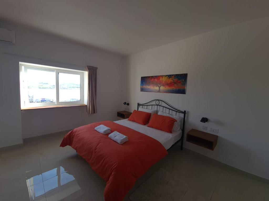 a bedroom with a bed with red pillows and a window at Sensi Hotel in Marsaskala