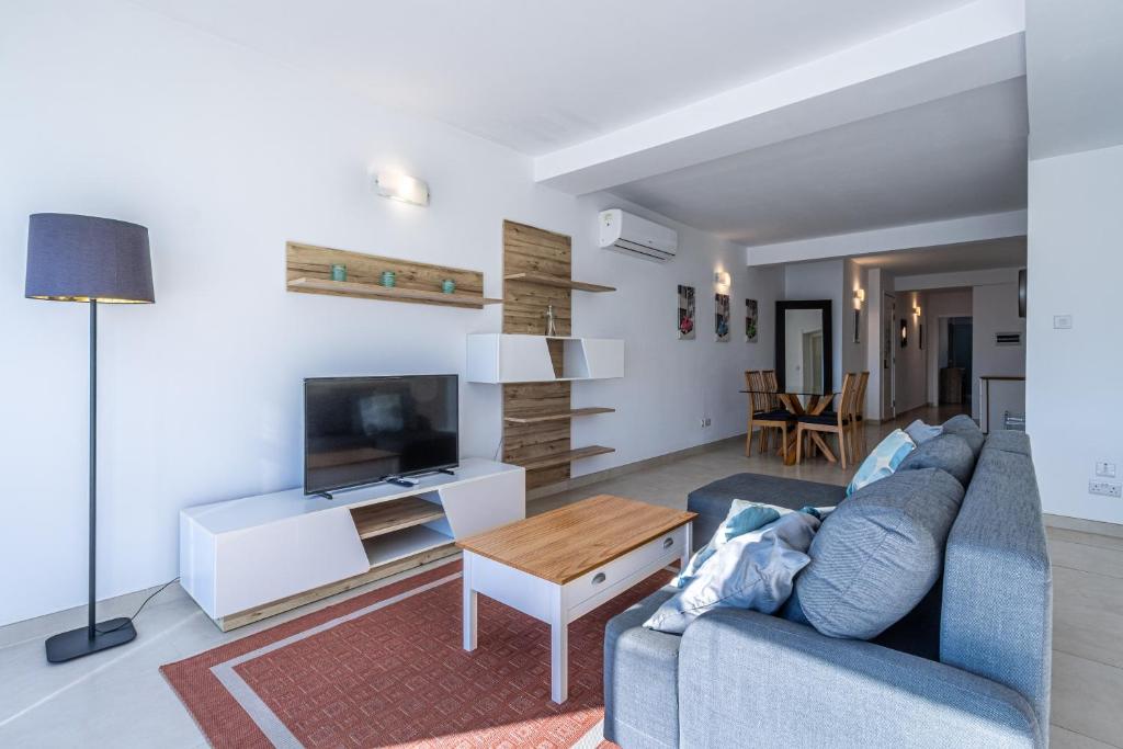 a living room with a blue couch and a tv at Bright and modern apartment in St Julian's