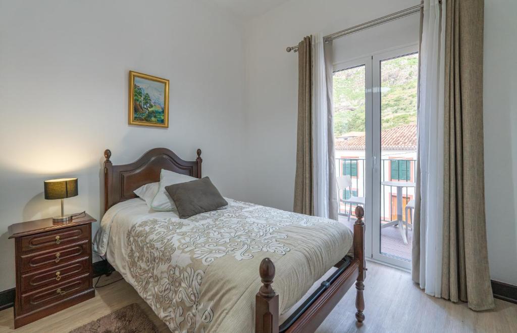 a bedroom with a bed and a large window at VillaHouse in São Vicente