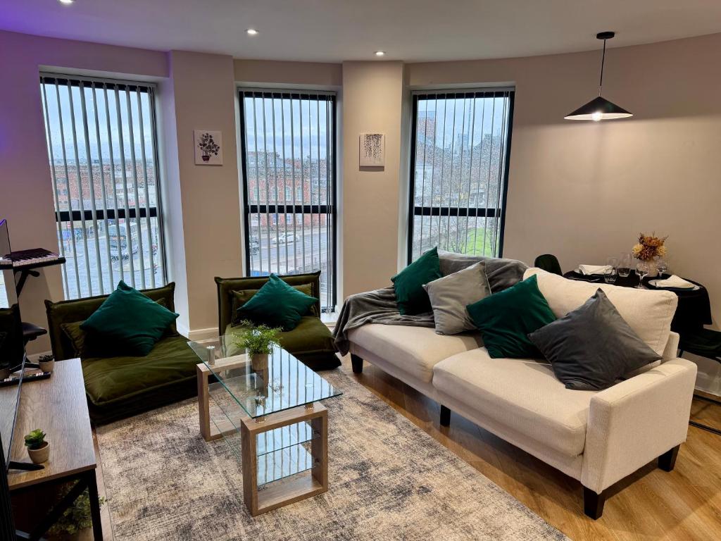 a living room with a white couch and green pillows at Central Leeds Apartment by the Arena with on-site parking in Leeds