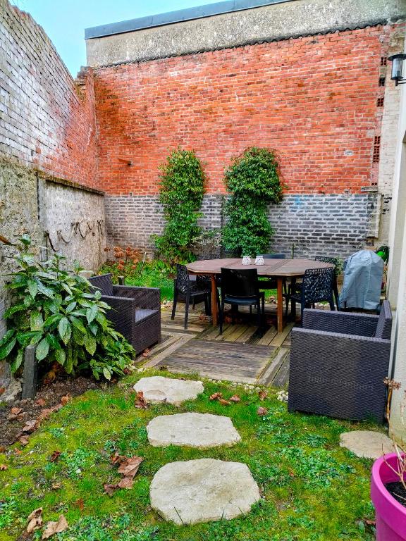 a patio with a table and chairs and a brick wall at Maison avec jardin, calme et ensoleillée à 2 minutes du centre-ville in Cabourg