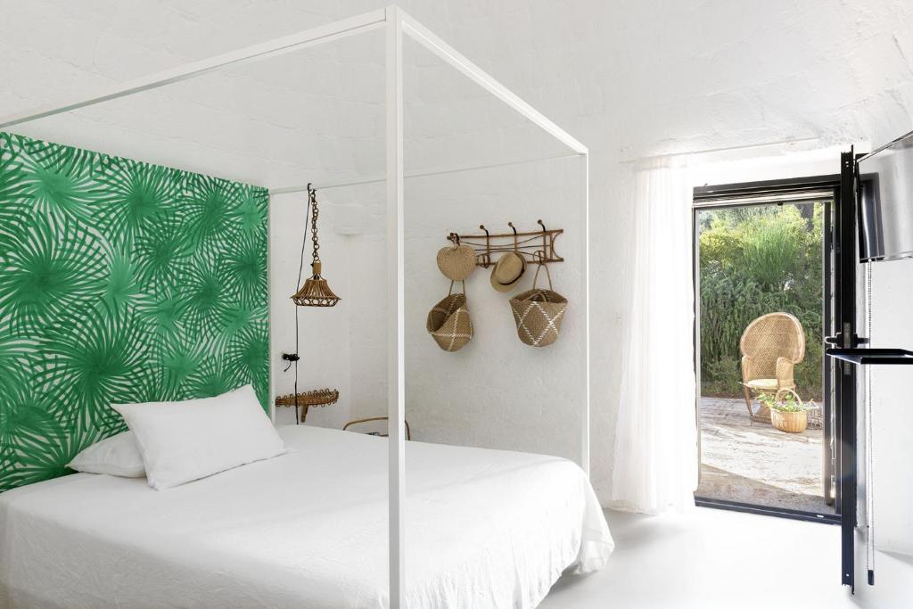 een slaapkamer met een wit bed en een groene muur bij Cocotrullo in Cisternino