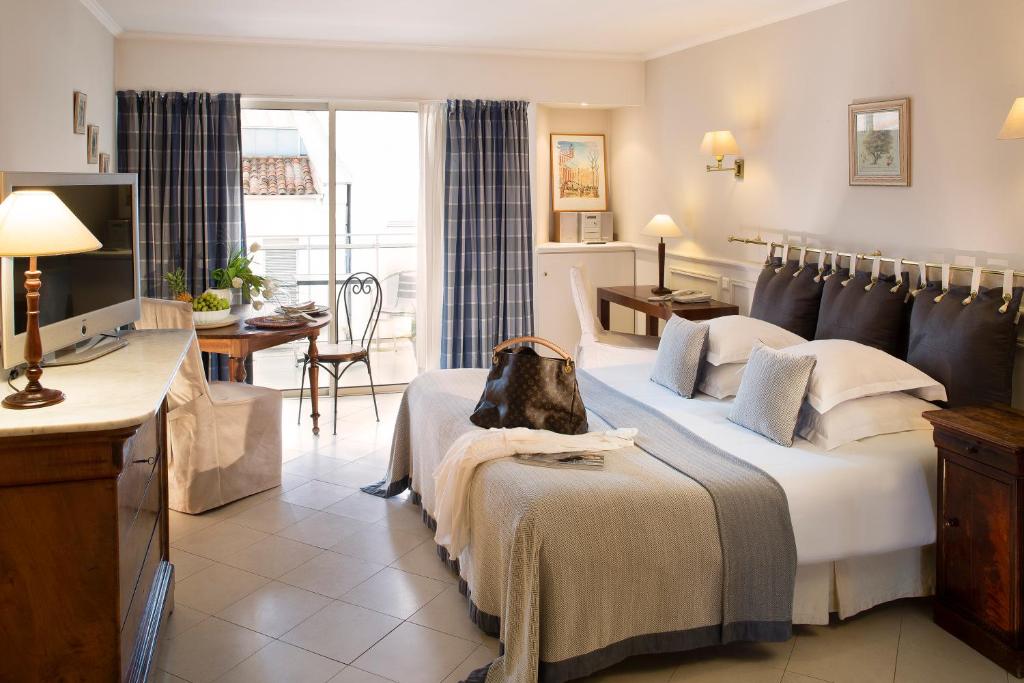 カンヌにあるヴィラ デステールの大きなベッドとデスクが備わるホテルルームです。