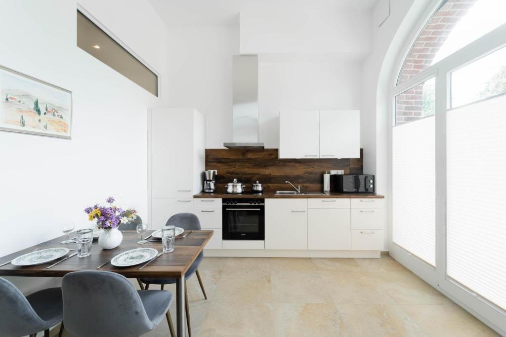 een witte keuken met een houten tafel en stoelen bij Ferienwohnung Marder in Münster