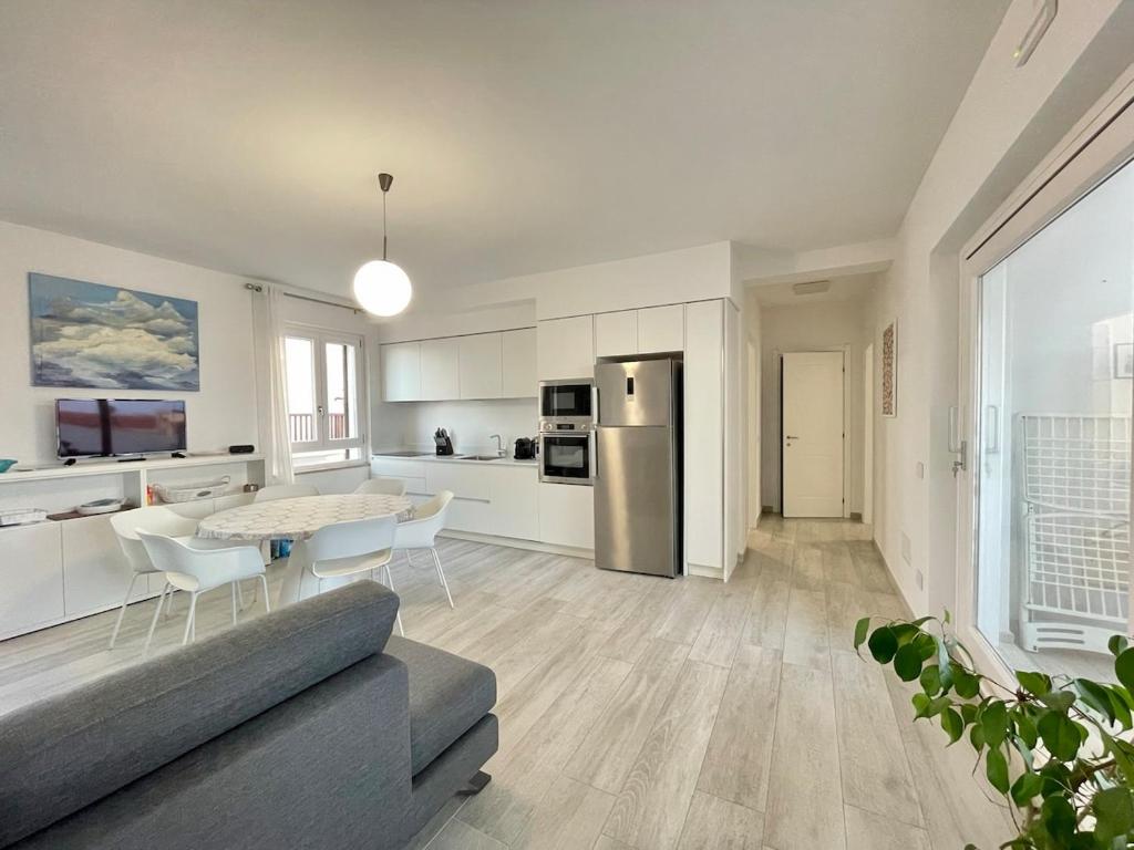 a kitchen and living room with a table and a refrigerator at IDA PALACE, nuovo appartamento deluxe fronte mare in Stintino