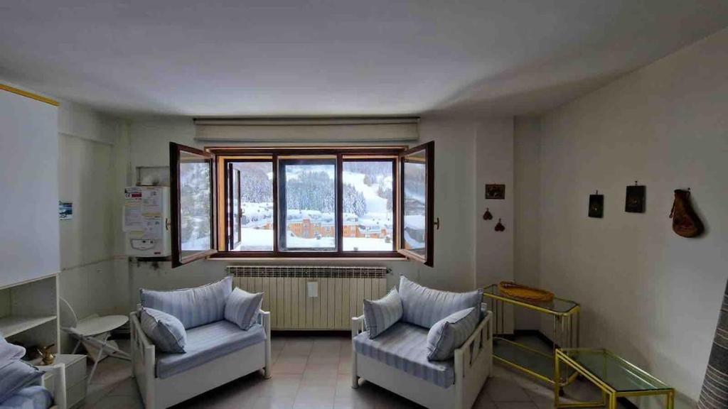 a living room with two chairs and a window at Bilocale in residence San Nicola 3 in San Massimo