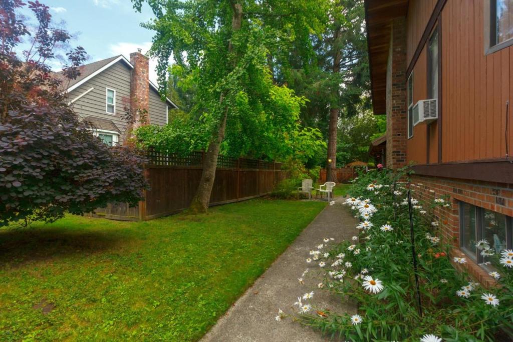 ein Hof eines Hauses mit einem Zaun und Blumen in der Unterkunft Cole's Bay Vacation Retreat Petie's Cottage in YYJ